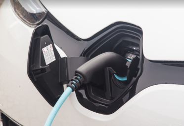 Close-up photograph of Electric Vehicle chargeing port with charging cable plugged into it.